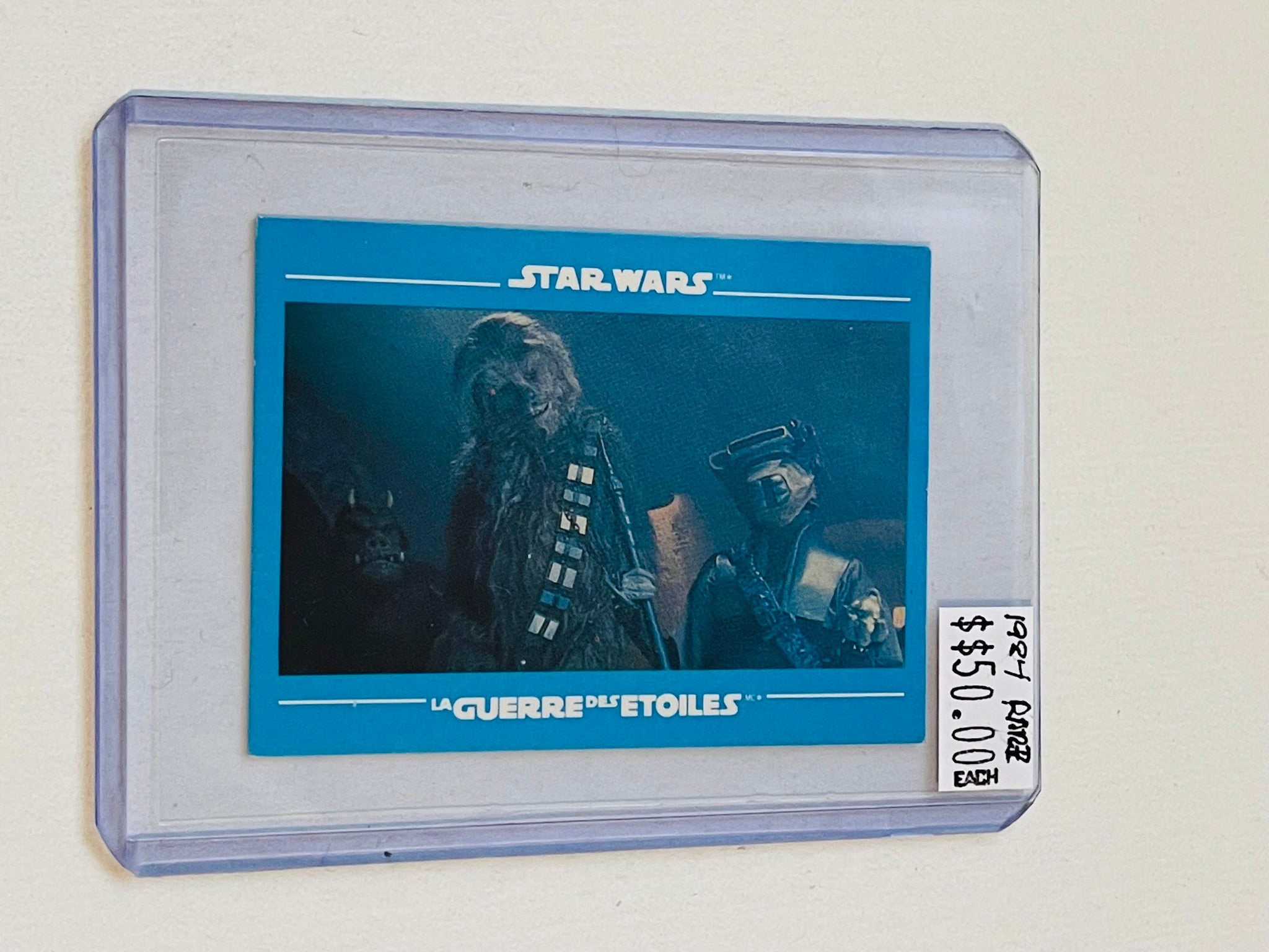 A trading card featuring an image of Chewbacca from Star Wars, encapsulated in a clear plastic sleeve with a blue backdrop.