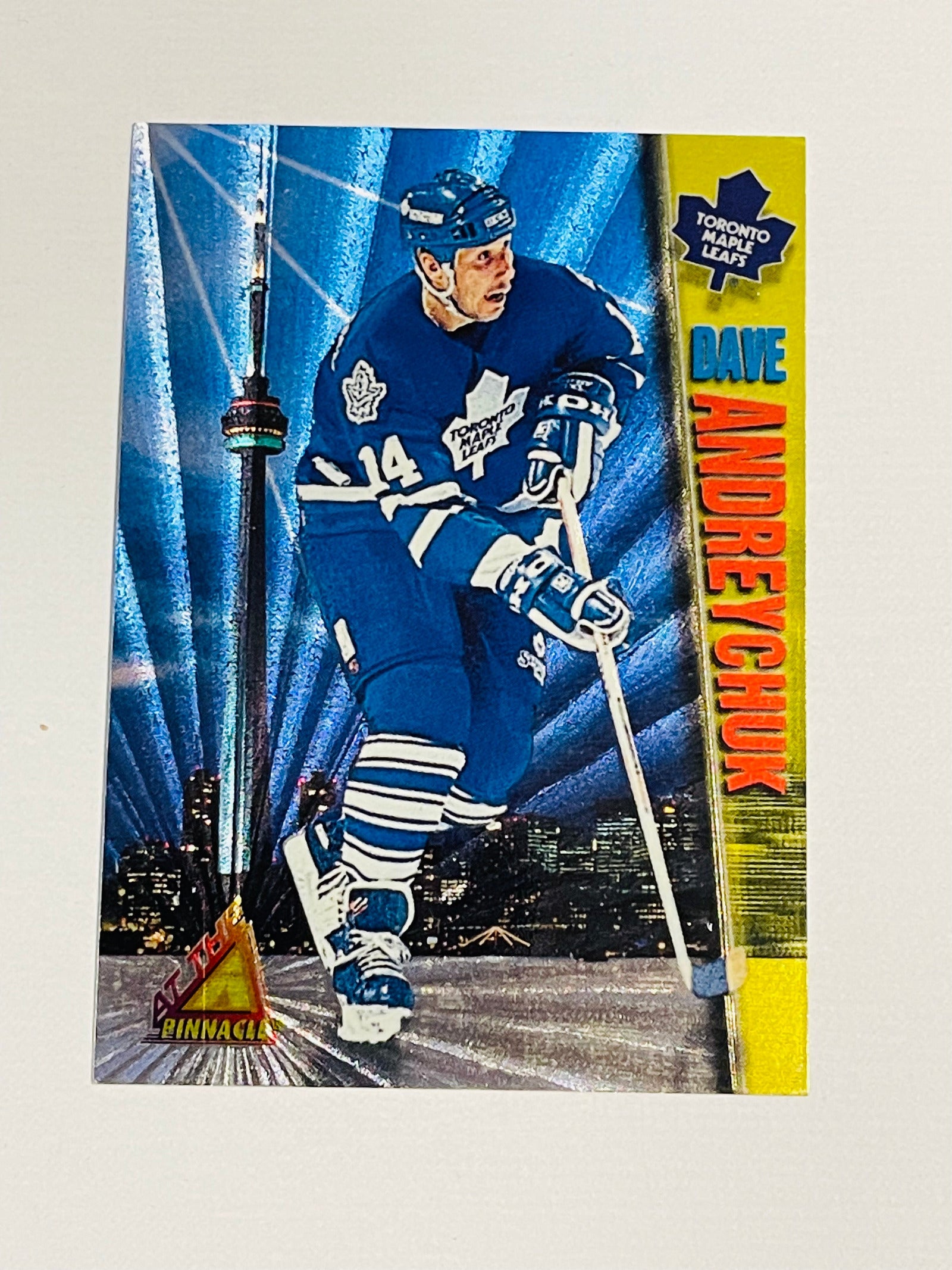 A trading card featuring Dave Andreychuk of the Toronto Maple Leafs with a blue background and a blurred image of a cityscape in the background.